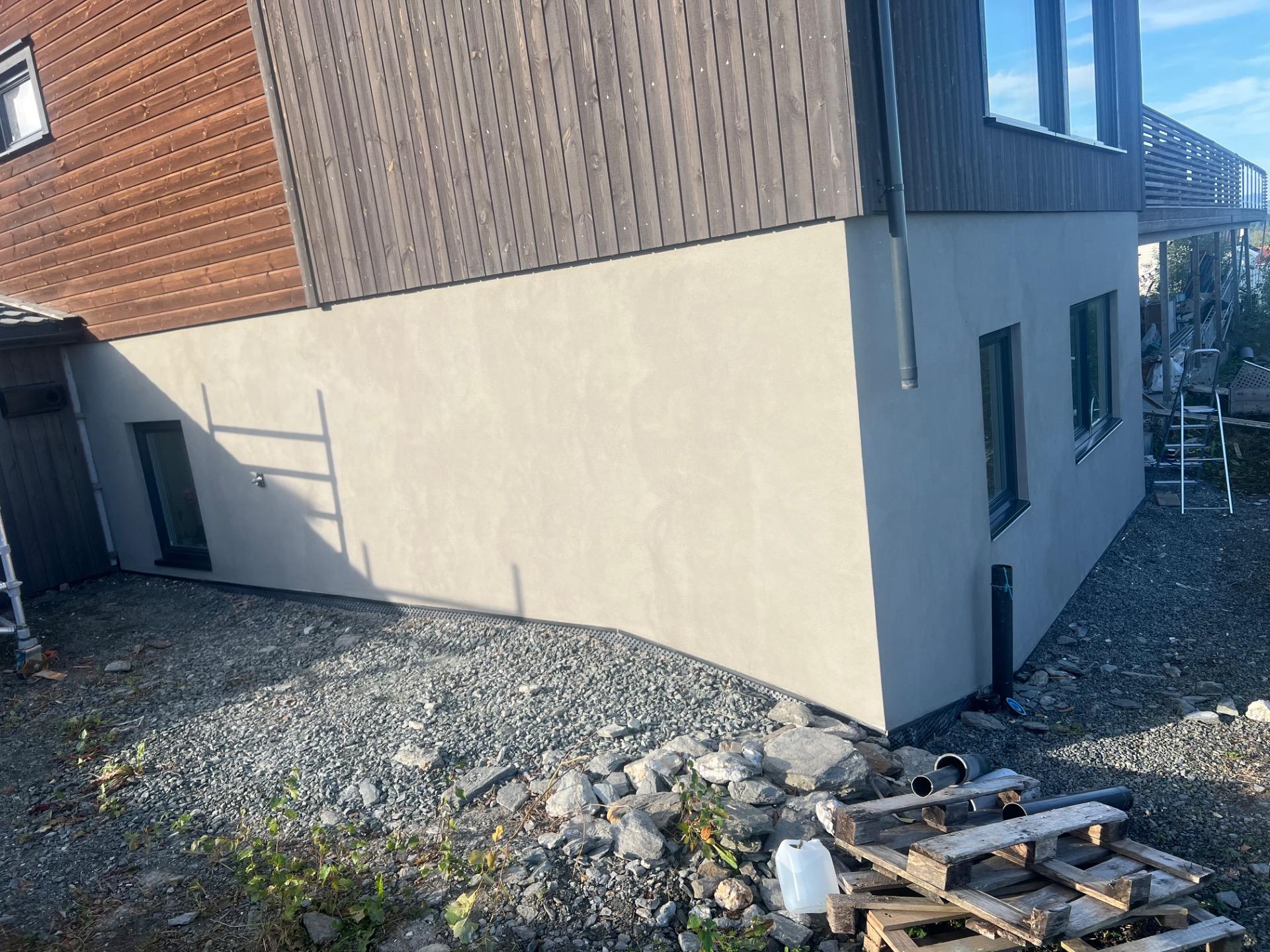 Nypusset grunnmur under et hus med trekledning
