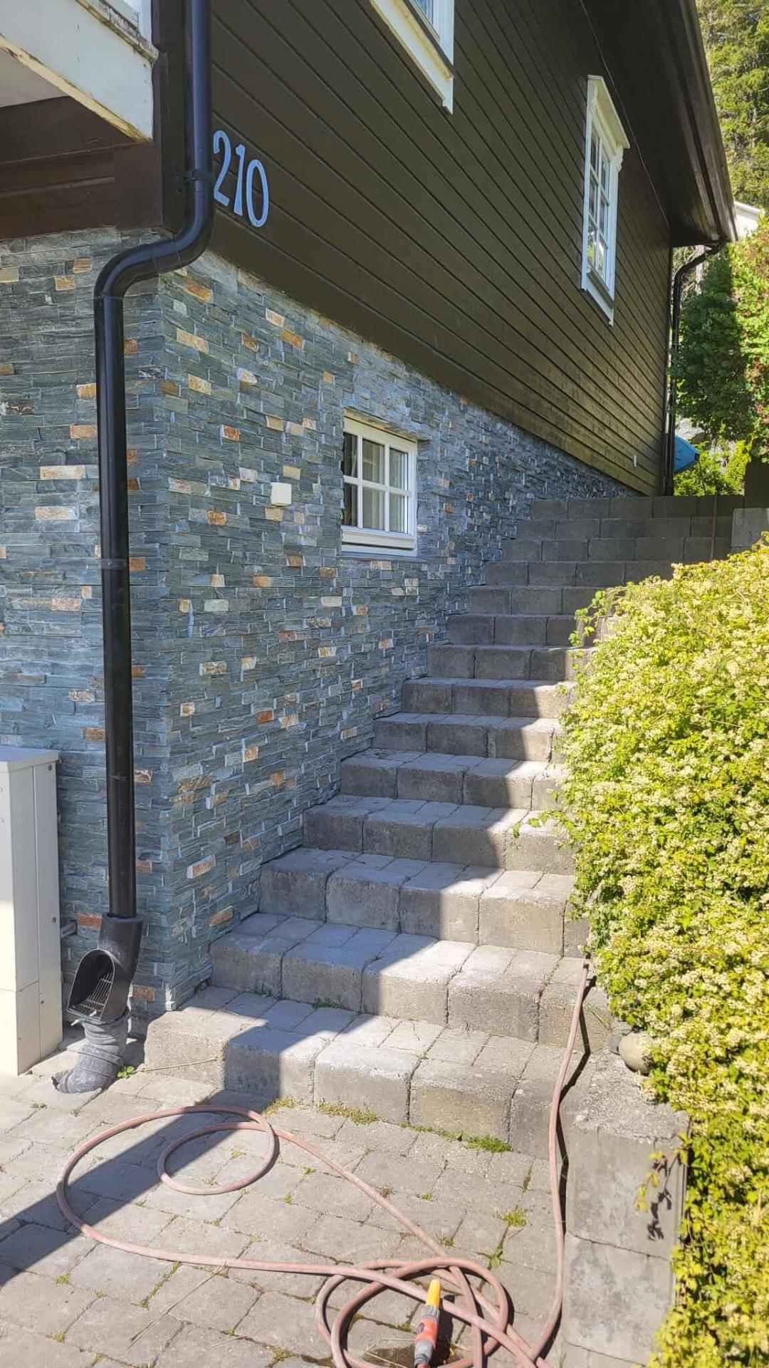Ny trapp og mur i skifer langs en mørk husvegg